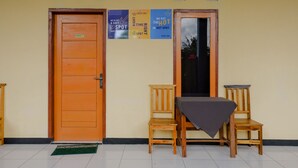 A room with two wooden doors, a small table with a checkered tablecloth, and a green mat on the floor. - SPOT ON 1976 Hamana Beach Inn (Pacitan)