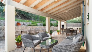 An outdoor patio with wicker furniture, a glass table, and potted plants. - SON VADO rural finca for 4 people in Santa Margarita with pool (Santa Margalida)