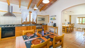 A kitchen with wooden cabinets, a stove, and a dining area with a table set for four. - SON VADO rural finca for 4 people in Santa Margarita with pool (Santa Margalida)