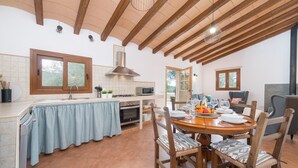 Une cuisine spacieuse avec des poutres en bois, un coin repas doté d’une table ronde et une vue sur l’extérieur.