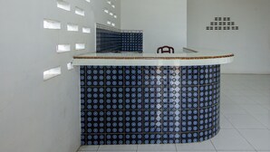 A reception area with a tiled counter, a chair, and a patterned wall. - OYO 2069 Wisma Syariah Kampung Baru (Rantauprapat)