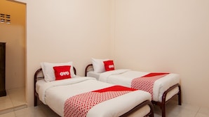 A hotel room with two single beds, each with a red and white patterned bedspread and matching pillows. - OYO 2069 Wisma Syariah Kampung Baru (Rantauprapat)