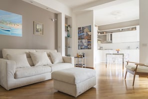 A modern living room with a sofa, ottoman, and a dining area with chairs and a table.