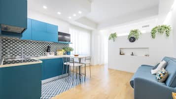 A modern kitchen with blue cabinets, a central island, and a dining area with chairs.