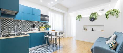 Une cuisine moderne avec des meubles bleus, un îlot central et un coin repas avec des chaises.