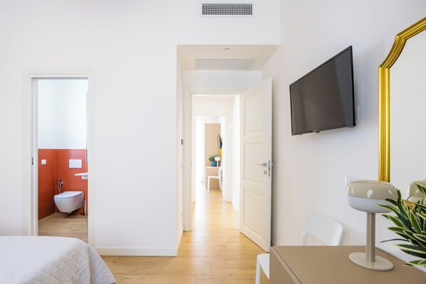 A hotel room with a bed, a desk, a TV, and a bathroom with a toilet and sink. - Residence Panoramic (Maiori)