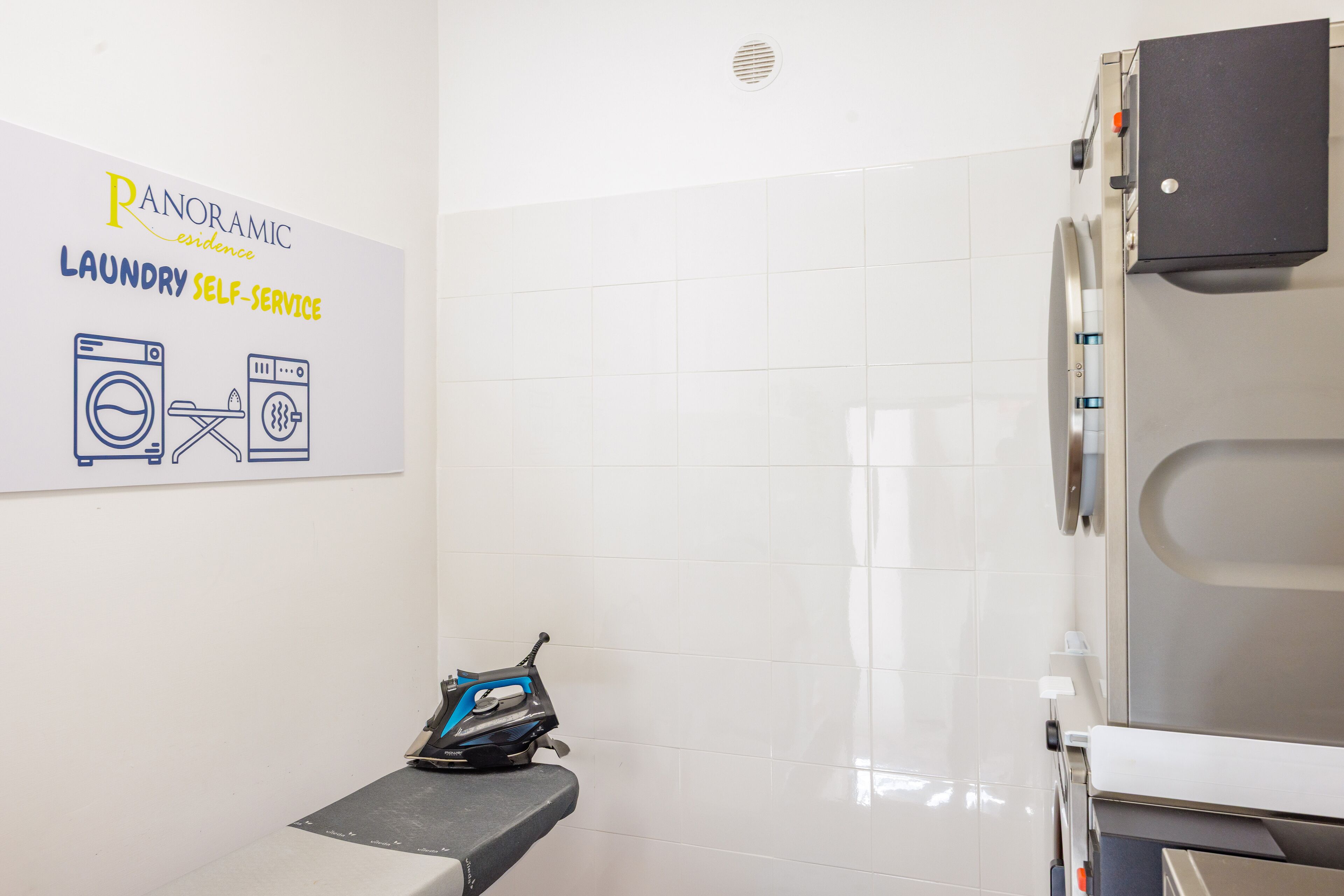 A laundry room with a self-service machine, a wall-mounted sign, and a bench.