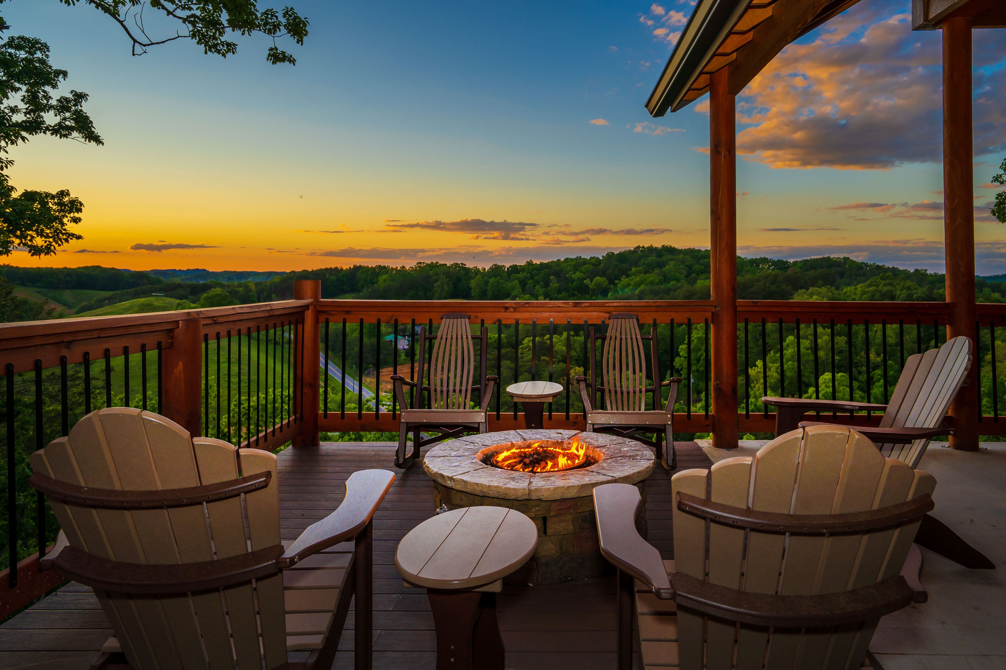 A deck with Adirondack chairs and a central fire pit, overlooking a scenic landscape.