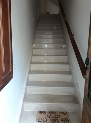 A staircase with a wooden handrail and a welcome mat at the bottom.