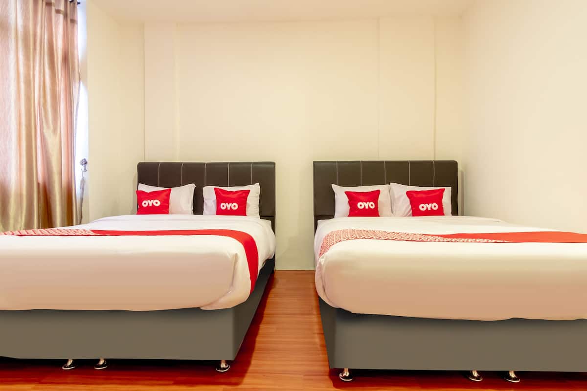 Een hotelkamer met twee bedden, elk voorzien van een hoofdeinde en kussens met het logo 'OYO'.