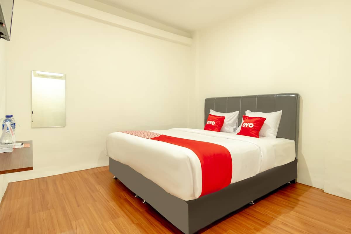 Een hotelkamer met een bed, nachtkastje en een spiegel aan de muur.