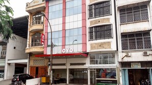 Un immeuble arborant une enseigne « OYO » bien visible, avec une façade moderne dotée de grandes fenêtres et d’un balcon.