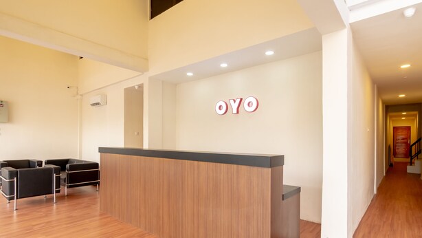 Un espace d’accueil avec un comptoir de réception en bois, un canapé noir et une enseigne fixée au mur sur laquelle on peut lire « OYO ».