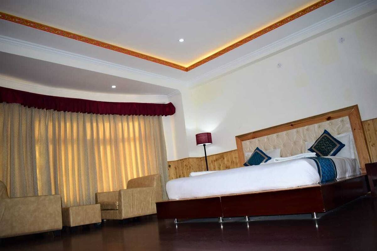 Ein Hotelzimmer mit einem großen Bett, zwei Sesseln, einem hölzernen Kopfteil und einer roten Lampe.