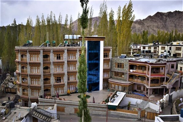 A multi-story building with a central atrium, surrounded by smaller structures, set against a mountainous backdrop.