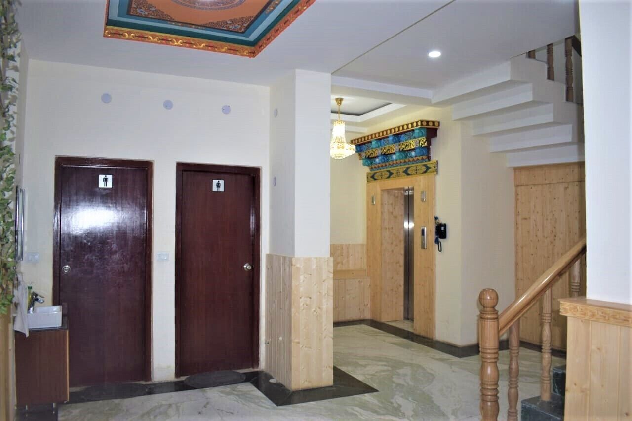 A hotel lobby with two wooden doors, a staircase, and a decorative ceiling.