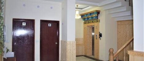 A hotel lobby with two wooden doors, a staircase, and a decorative ceiling.