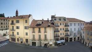 Vista de una calle en un pueblo europeo, con edificios que tienen balcones y una plaza central.