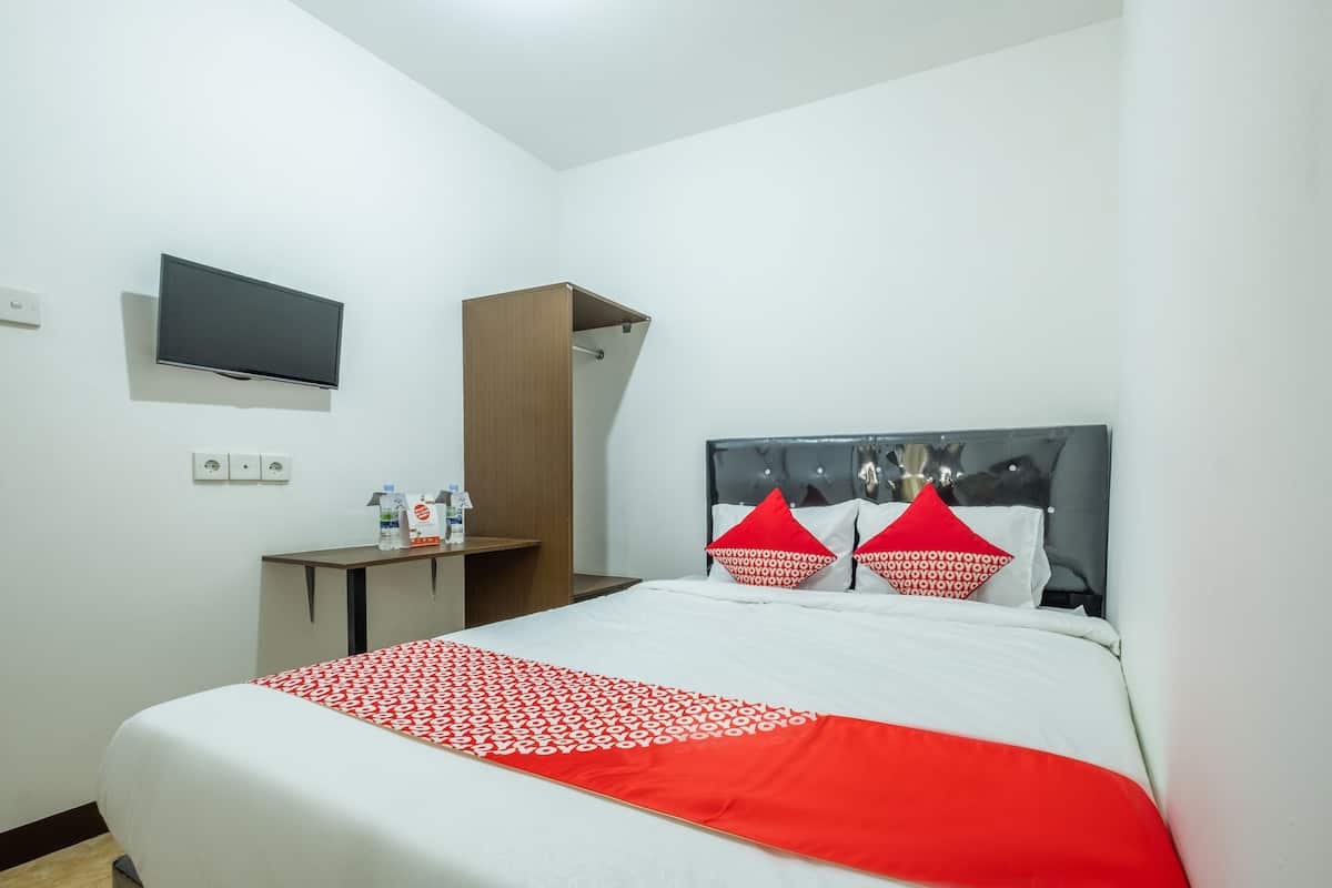 Une chambre d’hôtel équipée d’un lit, d’un téléviseur fixé au mur, d’un petit bureau et d’une armoire.