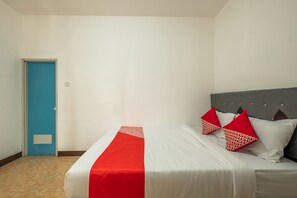 A hotel room with a bed, a blue door, and a white wall. - OYO 1460 Anyelir Residence (West Cirebon)