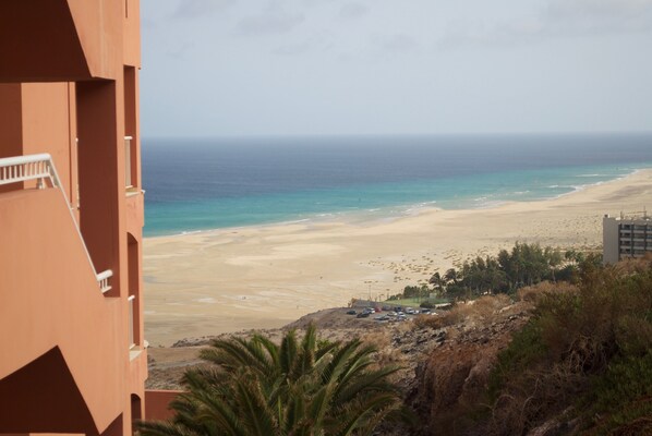 A view of a beach from a building with a balcony.
