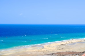 A beach with clear blue water, sandy shore, and a lifeguard tower.