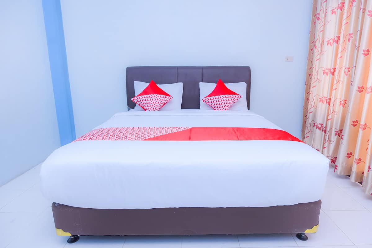 A bed with a white and red bedspread, two red pillows, and a grey headboard.
