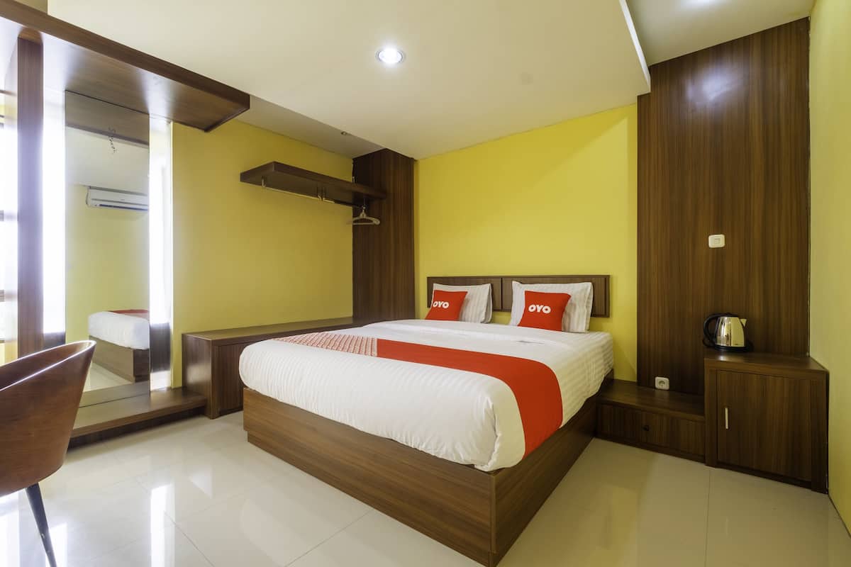 Une chambre d’hôtel avec un grand lit, une armoire en bois et un miroir.