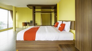 Quarto de hotel moderno com uma cama grande, uma escrivaninha e vista para a cidade.