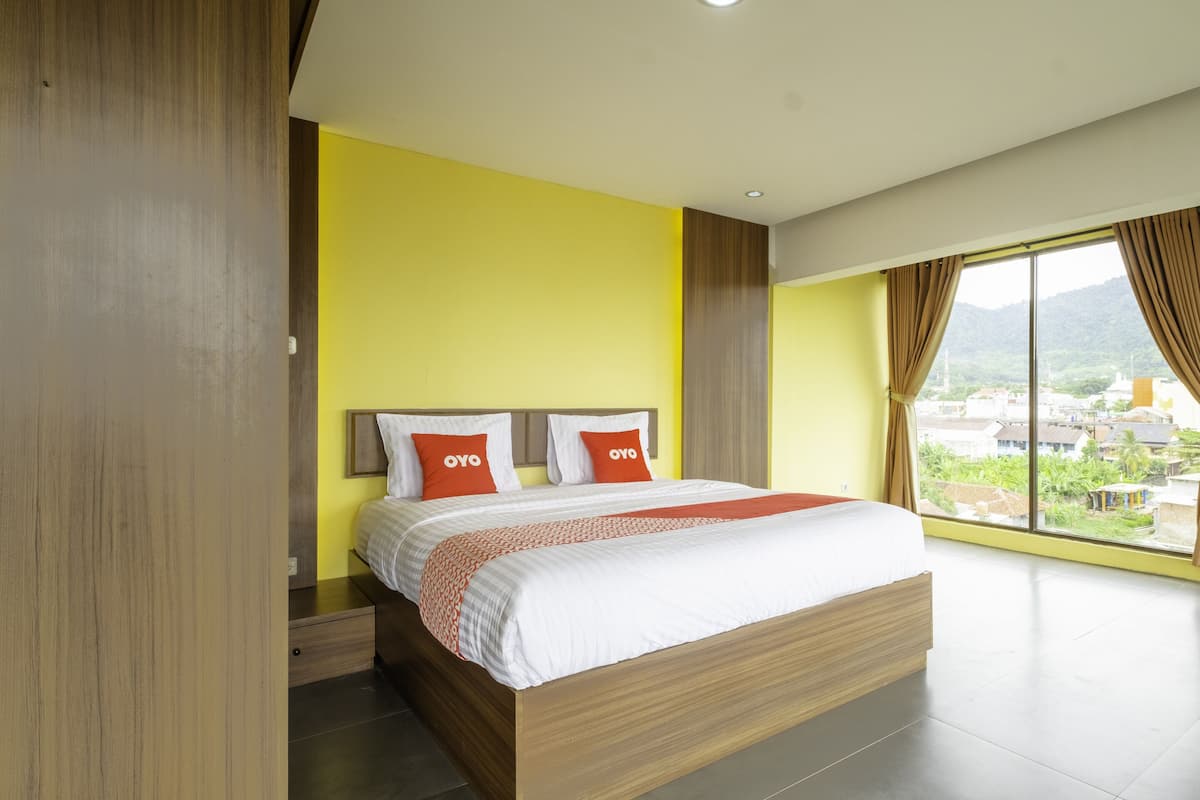 Une chambre d’hôtel moderne avec un grand lit, des murs jaunes et une vue sur la ville.