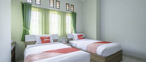 Habitación de hotel con dos camas, cortinas verdes y una ventana con marcos de madera.