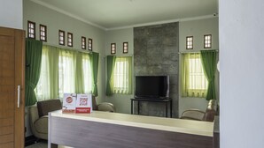 A hotel room with a reception desk, a television, and a stone accent wall.