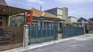 A gated residential area with a tiled roof house, a green fence, and a clear sky.