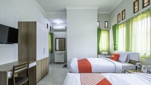 A hotel room with a bed, a desk, a chair, a TV, a bathroom, and a window with curtains.