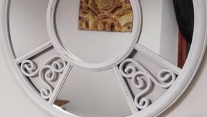 Un miroir rond orné d’un panneau décoratif central et de motifs en spirale sur les côtés.
