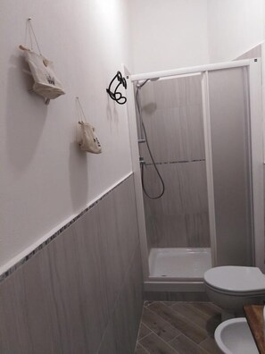 Une salle de bain avec une douche, des toilettes et un porte-serviettes.