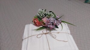 Une pile de serviettes blanches, attachées par une ficelle, posée sur un sol à motifs.