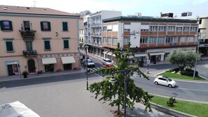 Une vue de rue avec des immeubles, un passage piéton et une voiture blanche en mouvement.