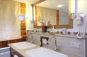 A bathroom with two sinks, a mirror, a towel rack, and a hairdryer. - Landgasthof Adler (Rammingen)