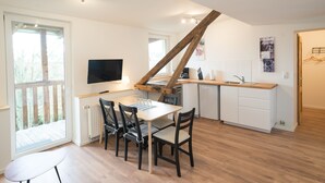 A modern kitchen with a wooden staircase, a dining area with chairs, and a TV mounted on the wall. - FeWo Engler Lüneburg Wallstraße (Lueneburg)