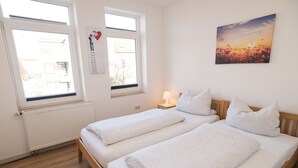 A room with two beds, a radiator, and a painting of a sunset. - FeWo Engler Lüneburg Wallstraße (Lueneburg)