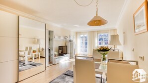 Un salon moderne avec un grand miroir, une table à manger avec des chaises, un canapé et un téléviseur.