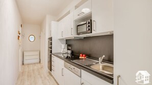 Une cuisine moderne avec des armoires blanches, un évier en acier inoxydable et un four encastré.