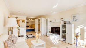 Un salon moderne avec un canapé, une table basse et une cheminée. On y trouve également un coin repas avec une lampe et une horloge au mur.