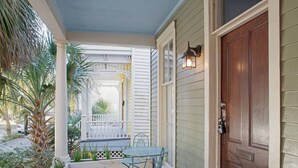 A covered porch with a table and chairs, a wooden door, and a small garden area with plants. - Huge 5 bed, 5 bath in Historic Downtown Savannah (Savannah)