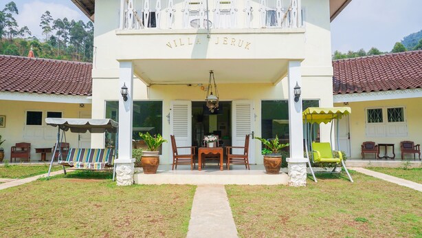A villa named "Villa Jeruk" with a covered entrance, a dining area with a table and chairs, and potted plants. - OYO 1785 Villa Jeruk Ciwidey (Ciwidey)