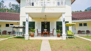 A villa named "Villa Jeruk" with a covered entrance, a dining area with a table and chairs, and potted plants. - OYO 1785 Villa Jeruk Ciwidey (Ciwidey)