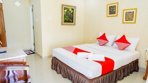 A hotel room with a neatly made bed, a wooden nightstand, and two framed pictures on the wall. - OYO 1785 Villa Jeruk Ciwidey (Ciwidey)