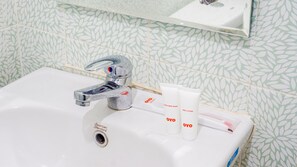 A bathroom sink with a chrome faucet, a mirror above it, and two OYO branded body lotion tubes on the sink. - OYO 1785 Villa Jeruk Ciwidey (Ciwidey)