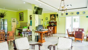 A spacious living room with a dining area, a kitchen, and a TV mounted on the wall. - OYO 1785 Villa Jeruk Ciwidey (Ciwidey)